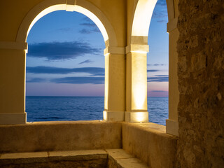 arch and window against sea at sunset