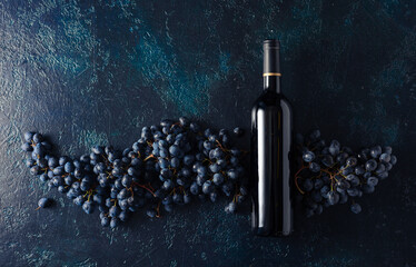 Bottle of red wine and grapes on a blue vintage background.