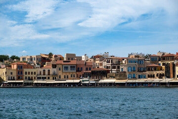 Greece, Chania Town Crete. View of outdoors cafe, seaside traditional building. Ripple sea water.