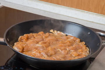 Shredded chicken for frying in a pan. The side dish is tomato juice.