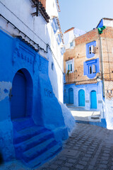 Narrow street with some houses with old doors, all painted blue in the medina of Chefchaouen, Morocco