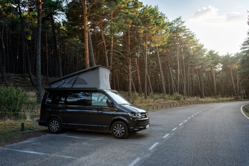 Modern new camper van with the roof open parked beside the forest in beautiful nature scene at...