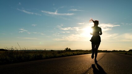 silhouette sports girl running along road sunset, american woman running along road, urban marathon...