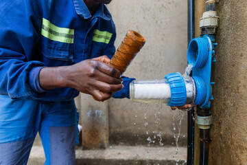 Closeup of African plumber showing one dirty and one clean filters. Changing water filters