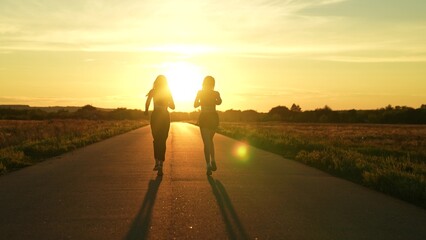 two friends running sunset, team group girls running sunset, silhouette athletic girls, teamwork healthy fitness lifestyle, legs athletes sports shoes, athlete exercise sunrise, warming up before