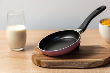 Breakfast background, small frying pan on a cutting board in the background a glass of milk and...