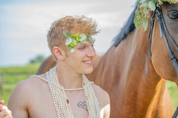 Portrait d'un jeune homme avec un cheval et des fleurs en couronne - obrazy, fototapety, plakaty