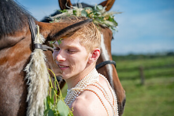 Jeune homme avec des perles et des chevaux avec des couronnes de fleurs - obrazy, fototapety, plakaty