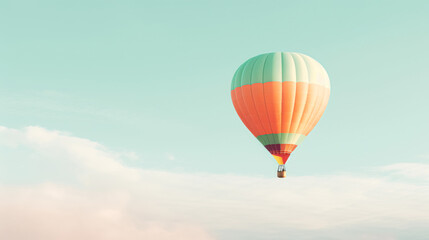 Fototapeta premium A colorful hot air balloon floats in a clear sky above soft clouds, conveying a sense of adventure and tranquility.