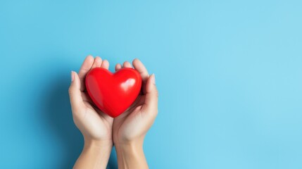 Hand holding a red heart on blue background, symbolizing appreciation for healthcare heroes on International Nurses Day.