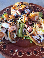 Delicious dish of Sopes and seafood tostadas that are a fried tortilla with beans, shrimp and...