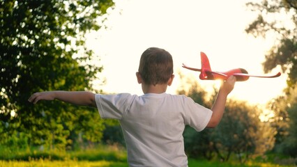 Happy child holds toy airplane on vacation in countryside. Small boy runs with airplane model....