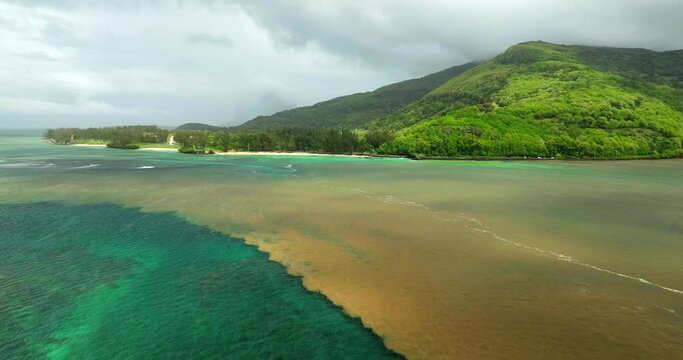 Beautiful aerial cinematic drone shot over Mauritius&rsquo; coastline capturing the halocline &mdash; a rare visual wonder where the river&rsquo;s freshwater merges with the ocean&rsquo;s salty waves, creating surreal color 