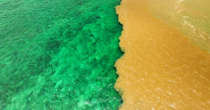 Drone footage flying over the coastline of Mauritius revealing the halocline phenomenon, where freshwater meets saltwater, forming vibrant layers of color and texture across the Indian Ocean surface.