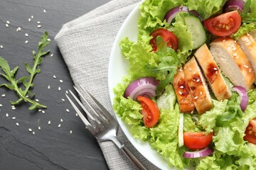Delicious salad with chicken and vegetables served on black table, top view