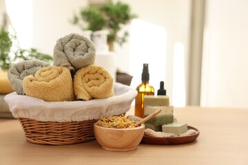 Dry flowers, soap bars, bottles of essential oils, jar with cream and towels on wooden table...