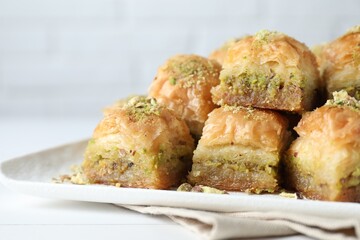 Delicious fresh baklava with chopped nuts on white table, closeup. Eastern sweets
