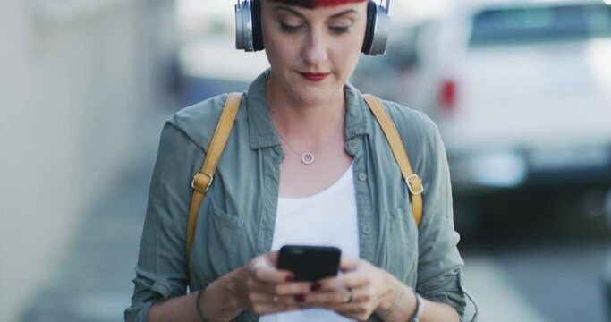 Headphones, typing and woman in city for communication and texting, message and streaming music on radio. Female person, smartphone and mobile app or website for conversation, playlist and podcast