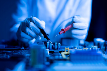 person holding multimeter tool and making  measurement on pcb computer board