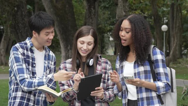 Group of young interracial diverse university students chatting together outside, engaging in a discussion together, college campus, enjoying campus recreation. Happy friends