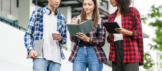Group of young interracial diverse university students chatting together outside, engaging in a discussion together, college campus, enjoying campus recreation. Happy friends