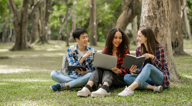 Group of young interracial diverse university students chatting together outside, engaging in a discussion together, college campus, enjoying campus recreation. Happy friends
