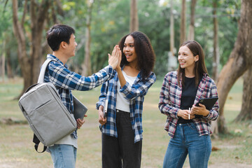 Group of young interracial diverse university students chatting together outside, engaging in a...