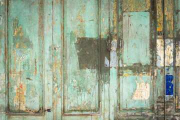 The background of the old door wall is made of wood, painted green, with clumps. Abstract wall texture backdrop.