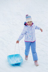 Sledding in winter. Time with family. Happy little girl holding .