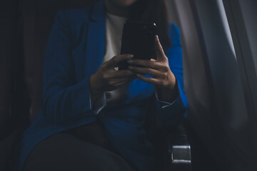 Young Asian business woman talking on smartphone, businesswoman working while flying at plane, Young woman using the internet at airplane, Air travel, long flight.