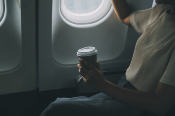 Asian woman enjoying enjoys a coffee comfortable flight while sitting in the airplane cabin,...