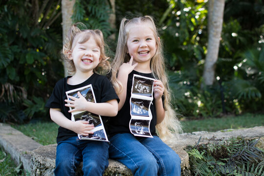 Pregnancy announcement by siblings. Social media pregnancy announcement. Big sister. The third child in a family. Two kids holding sonogram of a new baby 