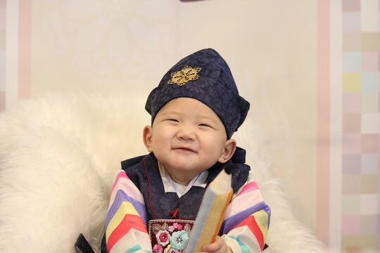 Celebrating Korean traditional 1st year birthday party with a grand ceremony called 'Doljanchi' (돌잔치). 1 year old Korean boy playing the highlight of the ceremony called 'Doljabi' (돌잡이).