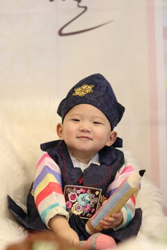 Celebrating Korean traditional 1st year birthday party with a grand ceremony called 'Doljanchi' (돌잔치). 1 year old Korean boy playing the highlight of the ceremony called 'Doljabi' (돌잡이).