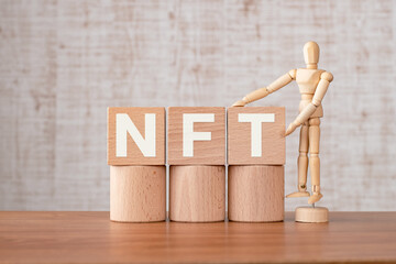 There is wood cube with the word NFT. It is an abbreviation for Non-Fungible Token as eye-catching image.