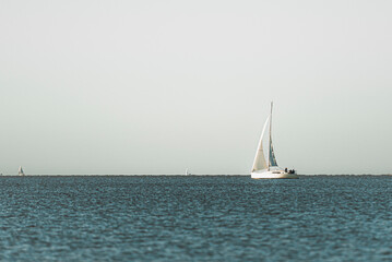 Barco blanco navegando en un mar tranquilo y azul, con un horizonte marcado y hermoso.