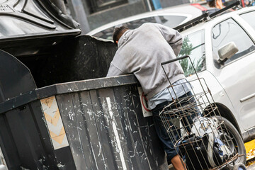 Persona en situación de calle buscando comida en la basura