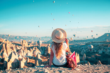 Kapadoya Cappadocia in Turkey- tourist young female sitting and watching colorful hot air balloons...