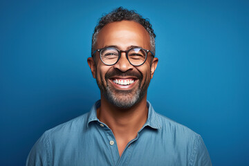 Obraz premium man with glasses on a blue background smiling at the camera