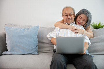 senior couple, elderly man and woman using laptop computer on sofa