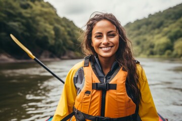 Happy young woman paddling a kayak along a mountain river. - obrazy, fototapety, plakaty