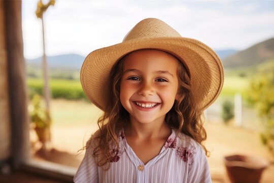 Portrait of a smiling little girl in a straw hat looking at the camera