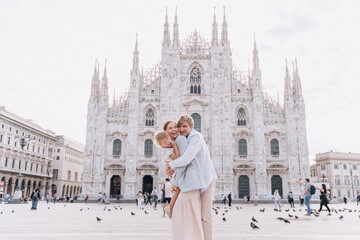 Happy hugging family with a child on Duomo square in Milan