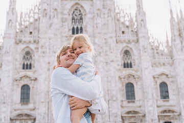 Fototapeta na wymiar A man hugs his little daughter in front of the Duomo Milan