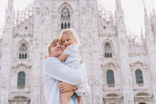 A man hugs his little daughter in front of the Duomo Milan