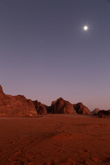 Moon shinning during red sunset upon the desert sand, Wadi Rum