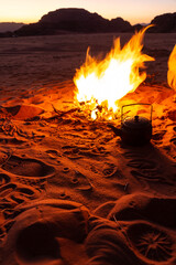 Tea pot next to fire pit surrounded by red desertic sand, Jordan