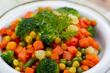 healthy vegetables. a large variety of brightly colored chopped vegetables lie in a white deep plate, with a bunch of parsley on top