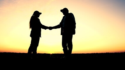 silhouette two farmers shaking hands sunset. agriculture concept. working people farm sunset....