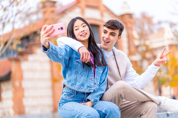 Joyful multi-ethnic couple taking a selfie in the street